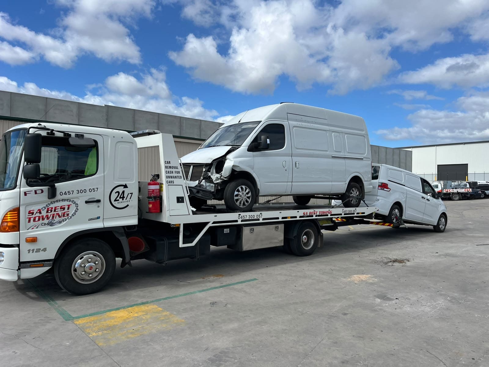 Crash-damaged white van on the SA Best Towing tray with a small white van on the rear lift
