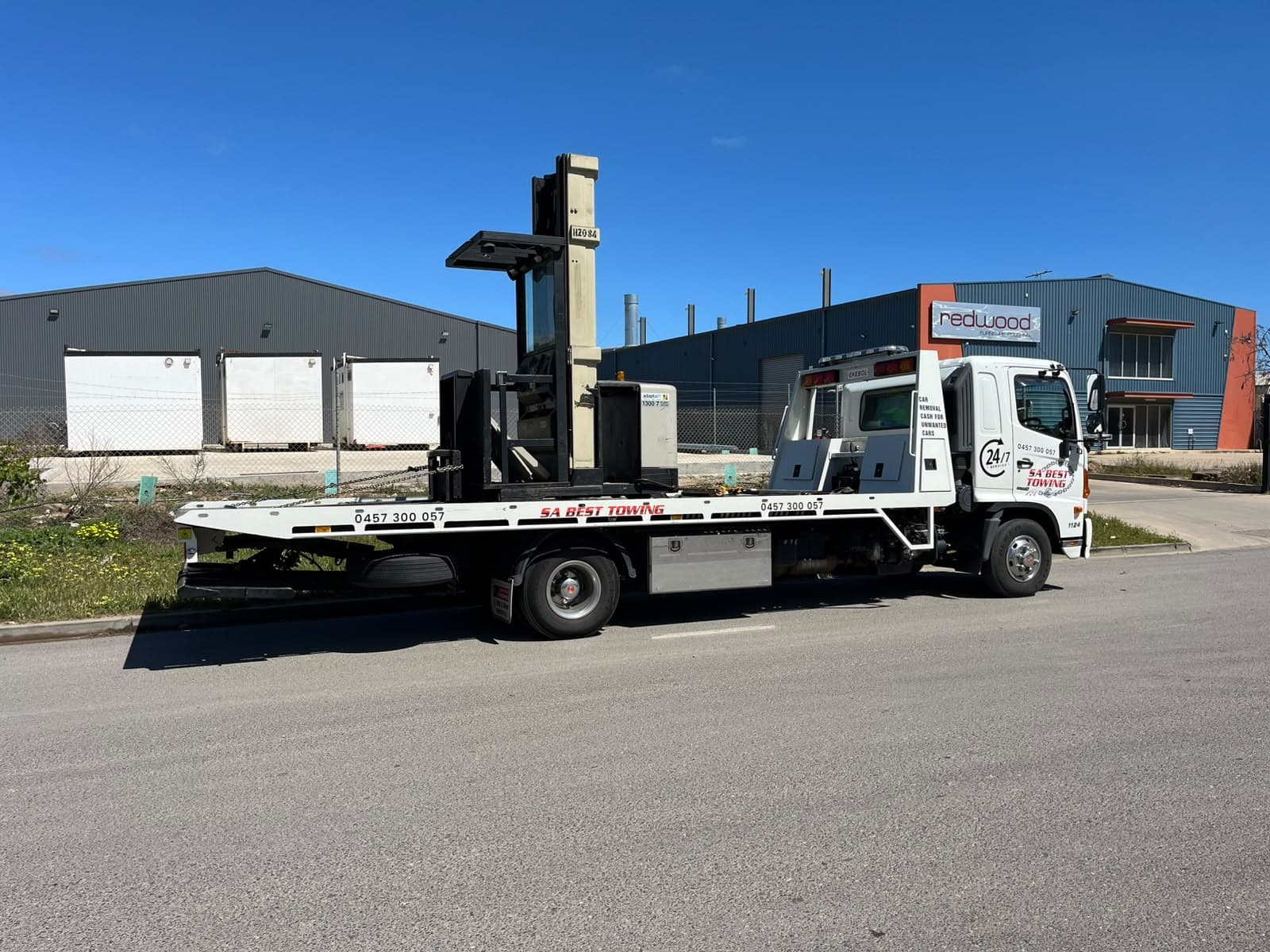 Older order picker with a tall mast on the tilt tray in an industrial estate