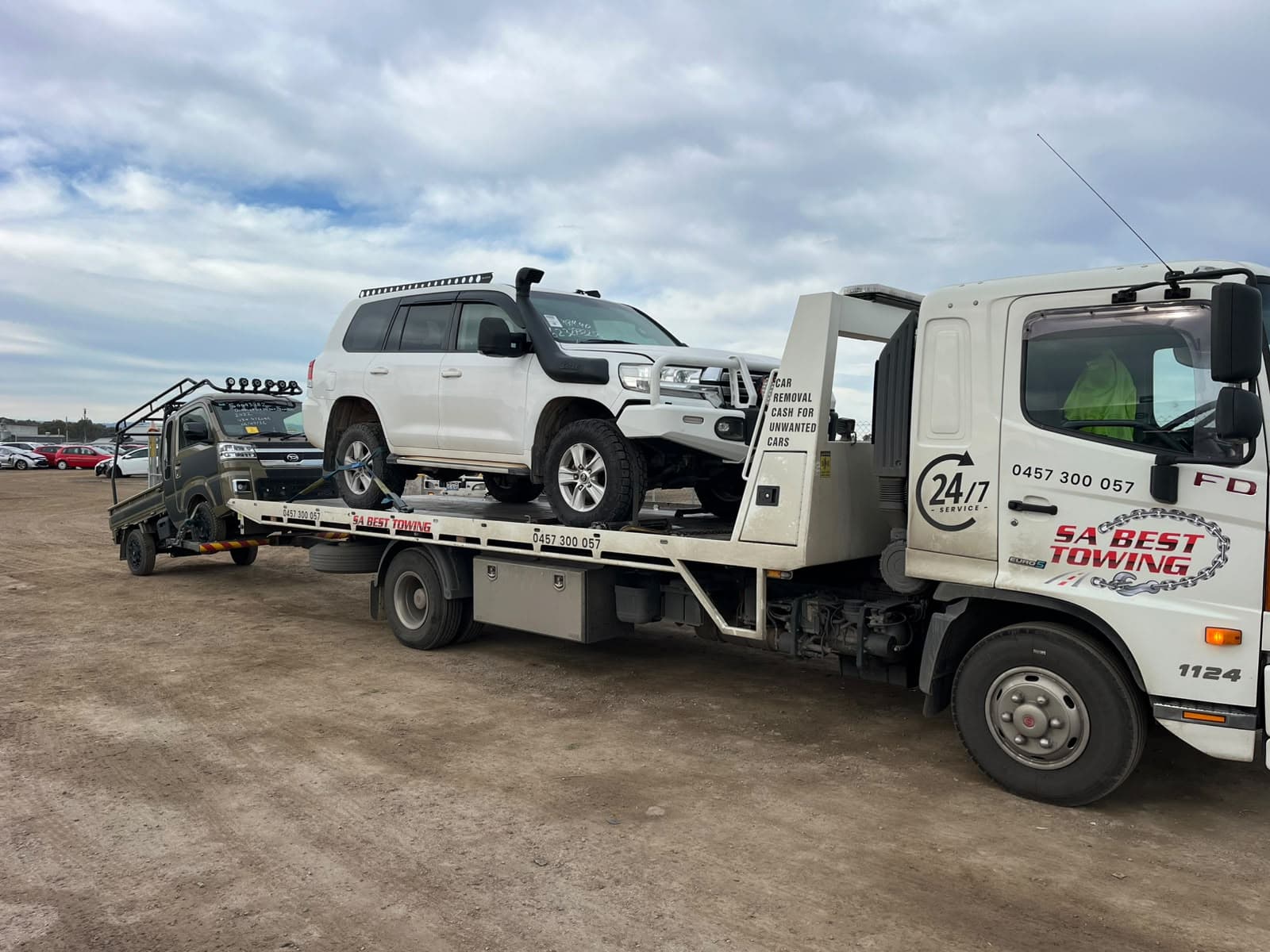 Lifted LandCruiser on the tray with a small flat-tray truck on the rear lift