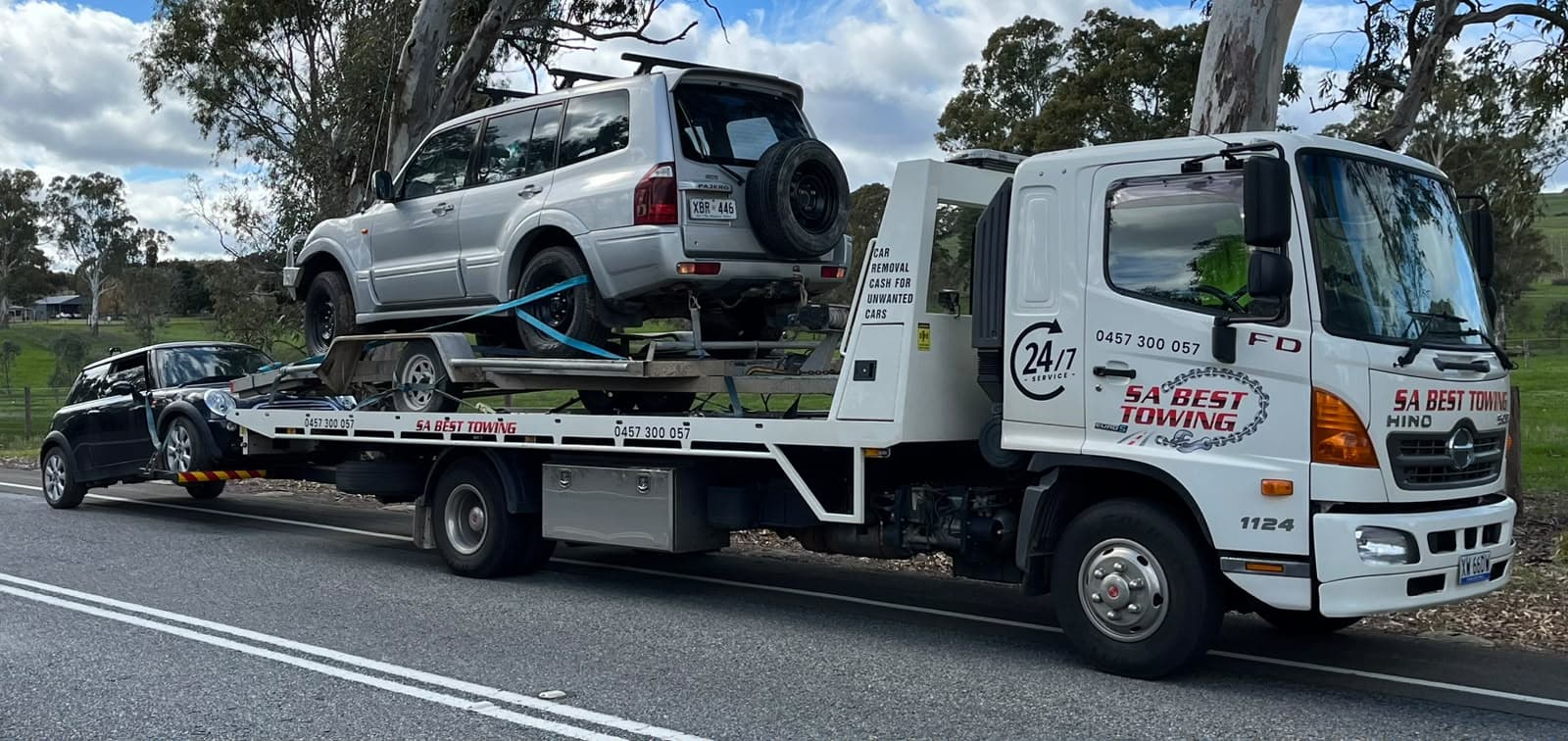 Silver Mitsubishi Pajero on a car trailer carried on the tray, with a Mini on the rear lift
