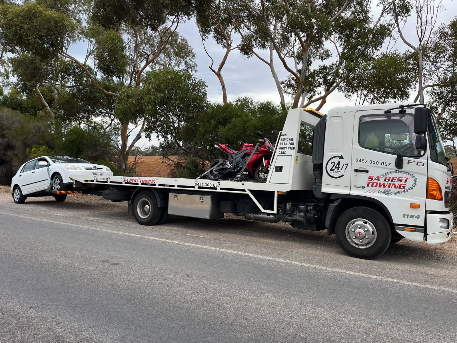 Sports motorcycle strapped on the tray with a white hatchback on the rear lift